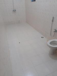 a bathroom with a toilet and a tiled floor at Heaven Goa Guesthouse in Benaulim