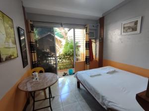 Habitación con cama, mesa y ventana en Mango House Apartments en Panglao City