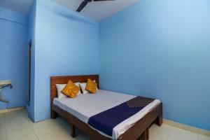 Cette chambre bleue comprend un lit avec des oreillers orange. dans l'établissement SPOT ON 61234 Pradeep Stays, à Bangalore