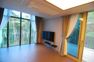 a living room with large windows and a flat screen tv at Forestel Meomul in Suncheon