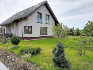 een wit huis met een grasveld ervoor bij Apartment with a swimming pool in Stepniczka in Stepnica