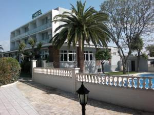 un bâtiment avec un palmier en face d'une clôture dans l'établissement Hotel Roca, à Vinaròs