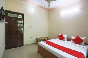 OYO 62761 Hotel Daksh في Mahendragarh: غرفة نوم بسرير ومخدات حمراء وبيضاء