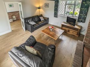 a living room with a leather couch and a table at Pixies Wood Cottage in Ludham