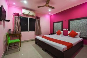 a bedroom with a large bed with pink walls at Hotel Kohinoor in Durgāpur