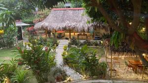 a garden with tables and chairs and a thatch roof at WAYANAY TAYRONA ECO HOSTEL in El Zaino