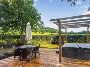 una terraza de madera con mesa y sombrilla en Cuckoo Lodge - Uk42541 en Winforton