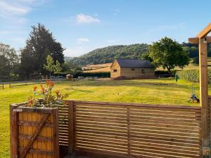 a wooden fence in front of a field with a house at Cuckoo Lodge - Uk42541 in Winforton