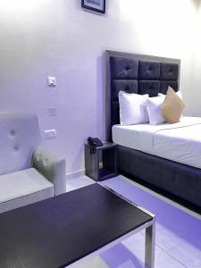 a room with a bed and a couch and a table at Rigg Hotel in Apapa Eleko
