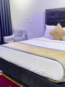 a large bed in a room with a chair at Rigg Hotel in Apapa Eleko