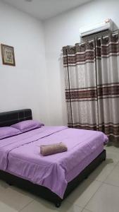1 dormitorio con 1 cama con sábanas y cortinas moradas en Nurkasih Homestay Jerantut, en Jerantut