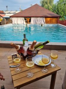 einen Tisch mit Weinflaschen und Gläsern neben einem Pool in der Unterkunft Vila Mario in Galaţi