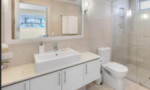 a bathroom with a sink and a toilet and a mirror at Monaco Caloundra in Caloundra