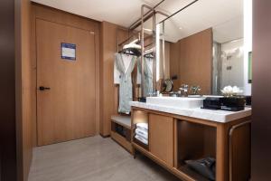 un bagno con un lavandino e un grande specchio di Hampton by Hilton Shenzhen Futian Port a Shenzhen