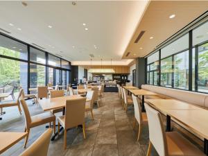 a dining room with tables and chairs and windows at Kanazawa Sainoniwa Hotel in Kanazawa