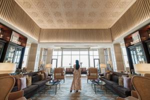 a woman is standing in a lobby with couches at JW Marriott Mussoorie Walnut Grove Resort & Spa in Mussoorie