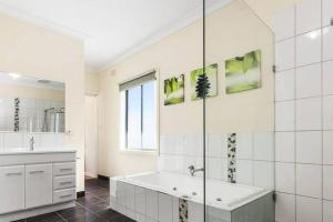 a white bathroom with a tub and a sink at Town, Train, Pubs & River all close by in Echuca