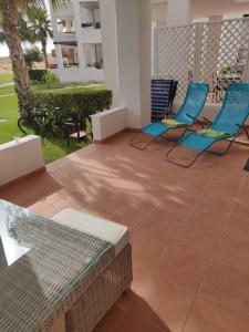 un patio con 2 sillas azules y una mesa en Casa Ana, en Murcia