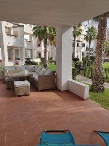un patio con sofás, mesas y palmeras en Casa Ana, en Murcia