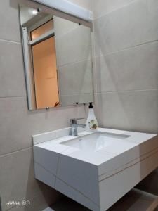 a bathroom with a white sink and a mirror at Appartemnt Essaouira welcome all in Essaouira