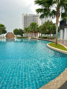 a large blue swimming pool with palm trees and buildings at Cosy Suite Almas Nusajaya in Nusajaya