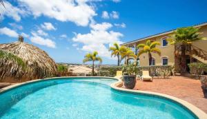 a swimming pool in front of a house with palm trees at Appartement Lora Jan Thiel Curacao in Jan Thiel