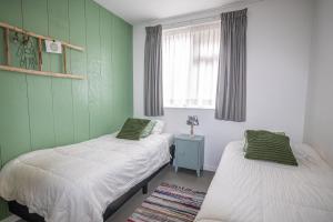 2 camas en una habitación con paredes verdes y ventana en Bodhi Beach House, en Egmond aan Zee
