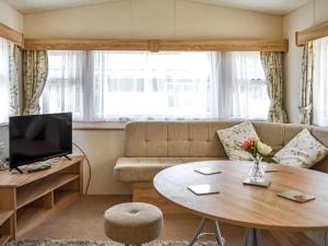 uma sala de estar com um sofá e uma mesa em Hillcrest Caravan - Uk44798 em Hemswell