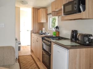 een keuken met een fornuis en een magnetron bij Hillcrest Caravan - Uk44798 in Hemswell