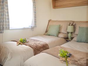 dwa łóżka w pokoju z kwiatami w obiekcie Hillcrest Caravan - Uk44798 w mieście Hemswell