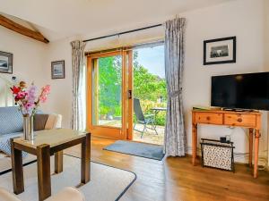 a living room with a television and a living room with a table at The Cottage Barn in Botesdale