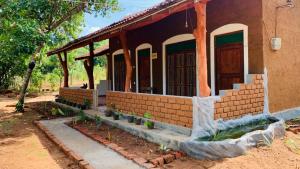 une maison en briques avec une terrasse couverte avec des plantes à l'extérieur dans l'établissement Sigiriya Chena Villa, à Sigirîya