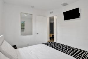 a white bedroom with a bed and a tv on the wall at 2Bd Holiday Retreat West Palm Beach Art Scene in West Palm Beach