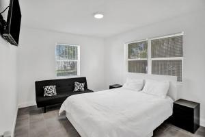 a bedroom with a white bed and a black chair at 2Bd Holiday Retreat West Palm Beach Art Scene in West Palm Beach
