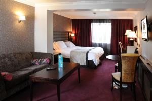 マリンガーにあるGreville Arms Hotel Mullingarのベッド、ソファ、テーブルが備わるホテルルームです。