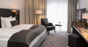 ein Hotelzimmer mit einem großen Bett und einem Stuhl in der Unterkunft Victor's Residenz-Hotel Teistungenburg in Teistungen