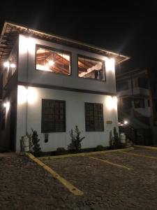 Un bâtiment blanc avec des lumières allumées la nuit dans l'établissement Sonho Real Suítes, à Lavras Novas