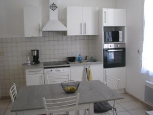 Una cocina con gabinetes blancos y una mesa con sillas. en Maison la Soleiade, en Carcassonne
