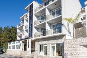um edifício de apartamentos branco com varandas e uma palmeira em Guest House Aria em Herceg Novi