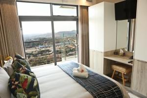 Cette chambre comprend un lit et une grande fenêtre. dans l'établissement Menlyn Trilogy - 2 Bedroom & Great Views - No Loadshedding, à Pretoria