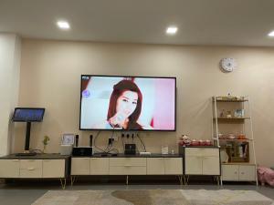 een flatscreen-tv aan een muur met een vrouw erop bij Double storey and half 4r3b karaoke lami in Cheras