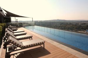 a swimming pool with lounge chairs on a building at Menlyn Trilogy - 2 Bedroom & Great Views - No Loadshedding in Pretoria