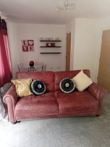 un sofá rojo con almohadas en la sala de estar en Stansted Airport Serviced Accommodation x DM for Weekly x Monthly Deals by D6ten Homes Ltd, en Takeley
