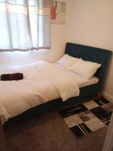 un letto con testiera blu e cuscini in una camera da letto di Stansted Airport Serviced Accommodation x DM for Weekly x Monthly Deals by D6ten Homes Ltd a Takeley