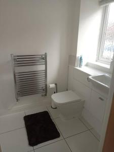 Baño blanco con aseo y lavamanos en Stansted Airport Serviced Accommodation x DM for Weekly x Monthly Deals by D6ten Homes Ltd en Takeley