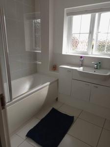 Baño blanco con bañera y lavamanos en Stansted Airport Serviced Accommodation x DM for Weekly x Monthly Deals by D6ten Homes Ltd, en Takeley