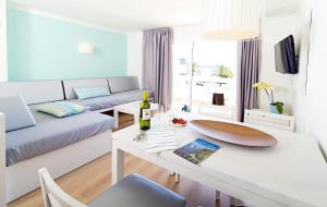 soggiorno con divano e tavolo con bottiglia di vino di Apartamentos Sivella a Port de Pollença