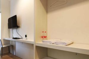 a room with white shelves with a tv and towels at Rumah Kayu Manis Bintaro in Jakarta +3 photos