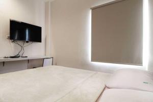 a white room with a bed and a flat screen tv at Rumah Kayu Manis Bintaro in Jakarta