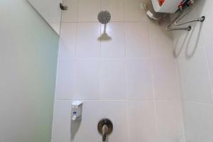 a white tiled bathroom with a shower with a fan at Rumah Kayu Manis Bintaro in Jakarta
